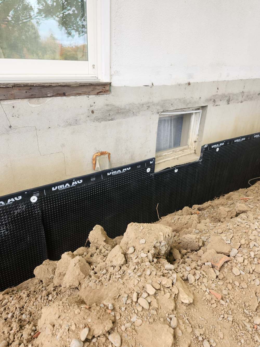 Foundation wrap installed below the old water line on a stucco foundation