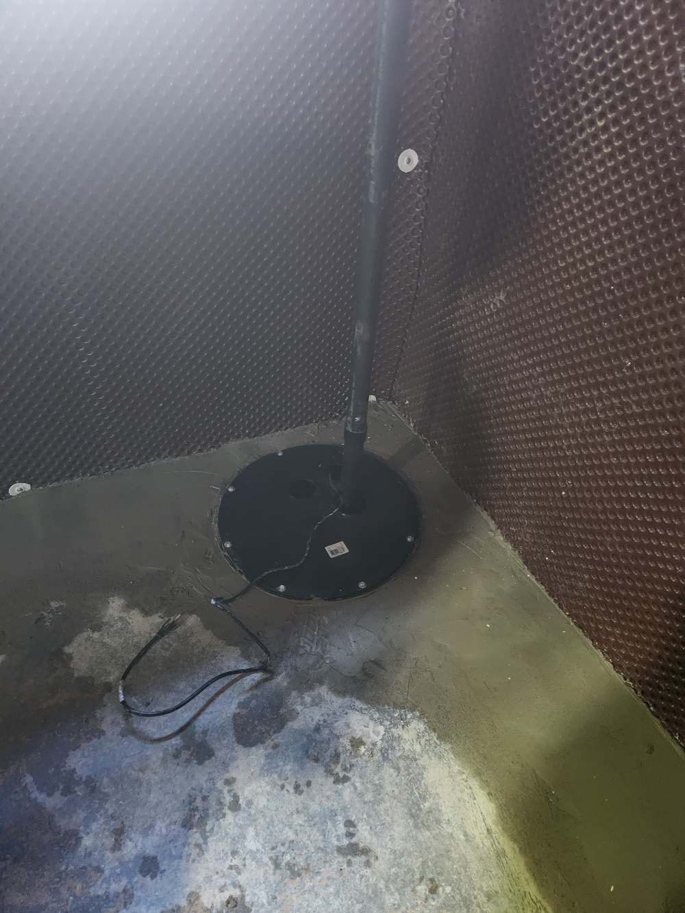 Installed sump pit with sealed lid and discharge pipe